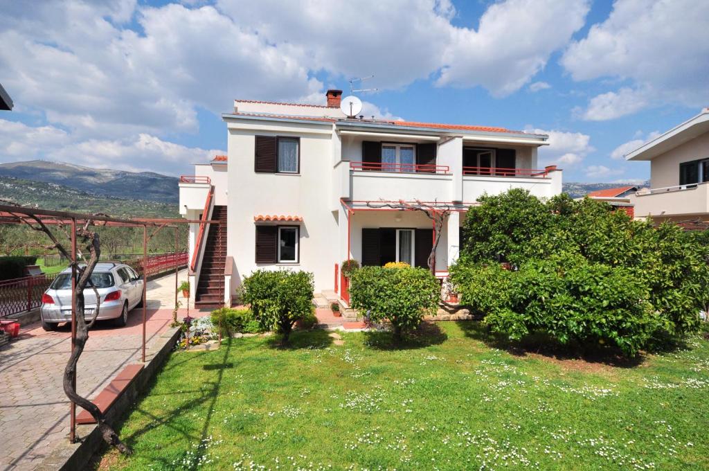 a white house with a car parked in a yard at Apartments Zizic in Kaštela