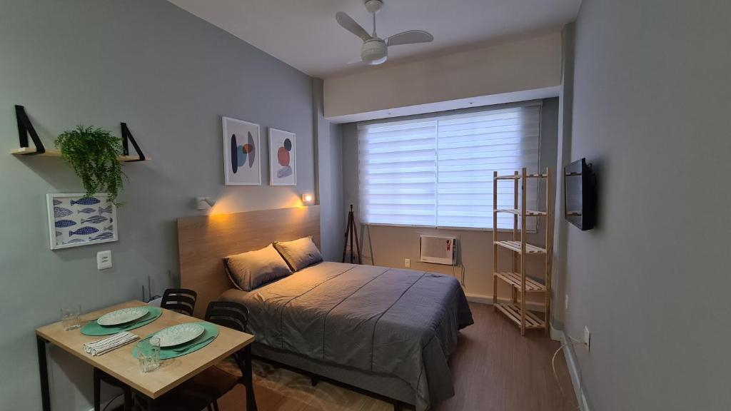 a small bedroom with a bed and a table at MARAVILHOSO ESTÚDIO- PRAIA DE BOTAFOGO in Rio de Janeiro