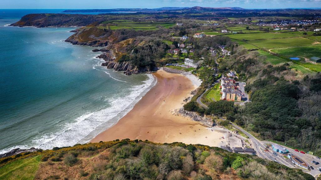 an aerial view of a beach next to the ocean at Caswell Beach Chalet 70 located in Gower Peninsula in Swansea