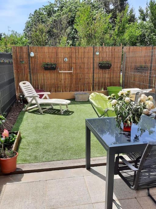 une cour avec une table, des chaises et une clôture dans l'établissement Maison avec jardin, à Lunel
