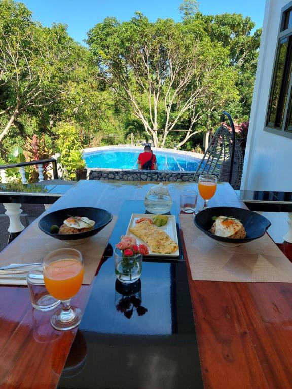 Zamboanguita的住宿－Matteo's hus VILLA RENTAL，游泳池旁的餐桌,供应食物和饮料