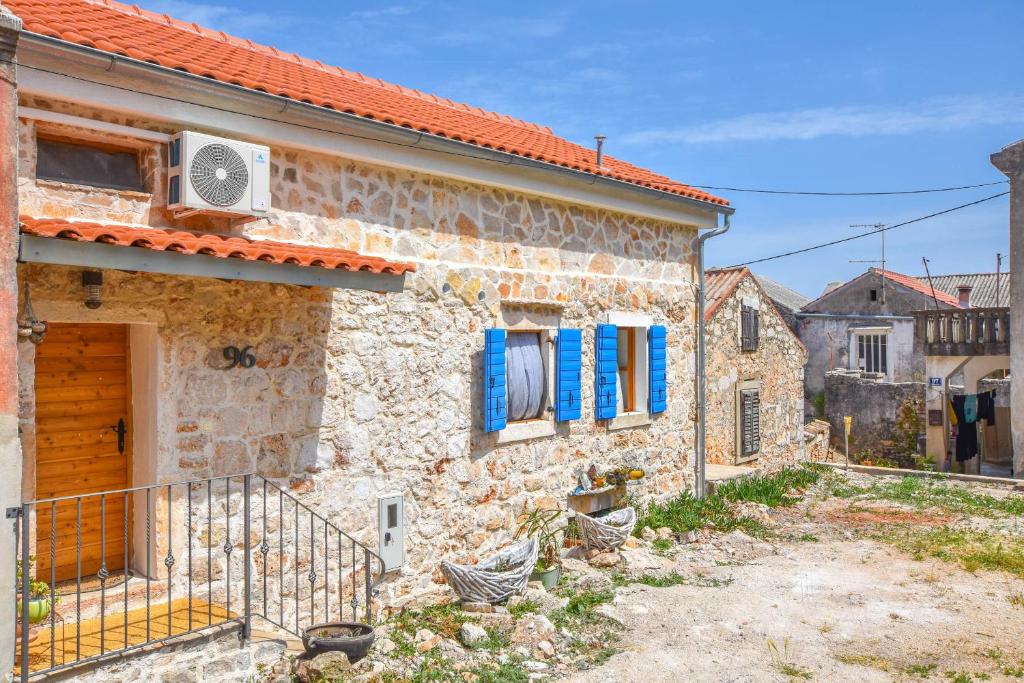 ein Steinhaus mit blauen Fensterläden an einem Gebäude in der Unterkunft Apartment Fjaka in Žman