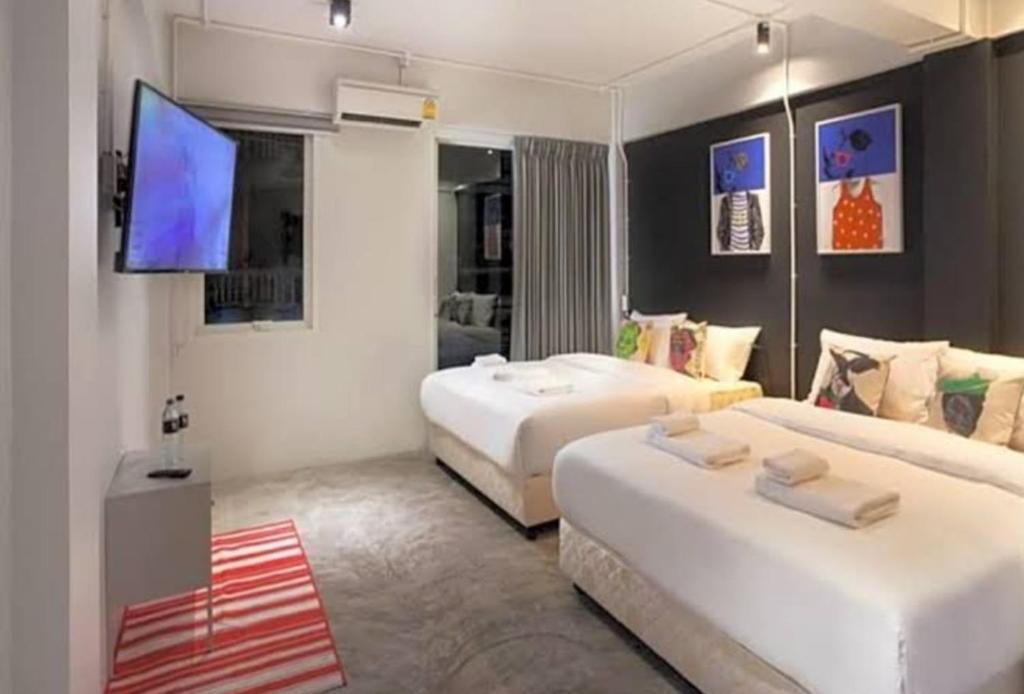 um quarto de hotel com duas camas e uma televisão de ecrã plano em Bella Ciao em Praia de Jomtien