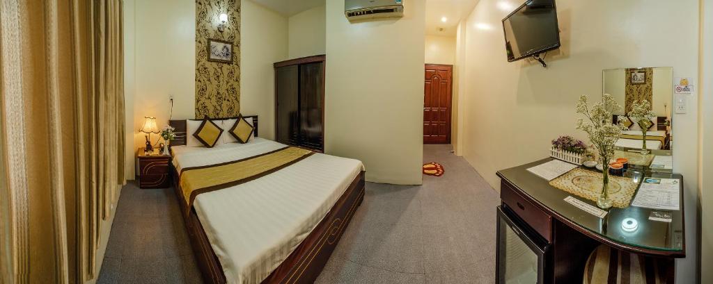 a bedroom with a bed and a desk with a television at Dong Bao Hotel in Chau Doc