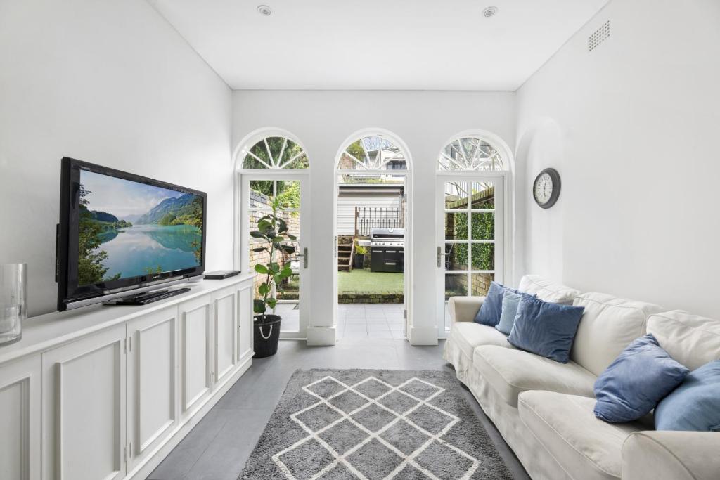 a living room with a couch and a flat screen tv at WIND85P - Pet Friendly Paddo Terrace in Sydney