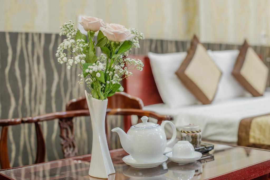 a vase of flowers on a table with a tea pot at Dong Bao Hotel in Chau Doc