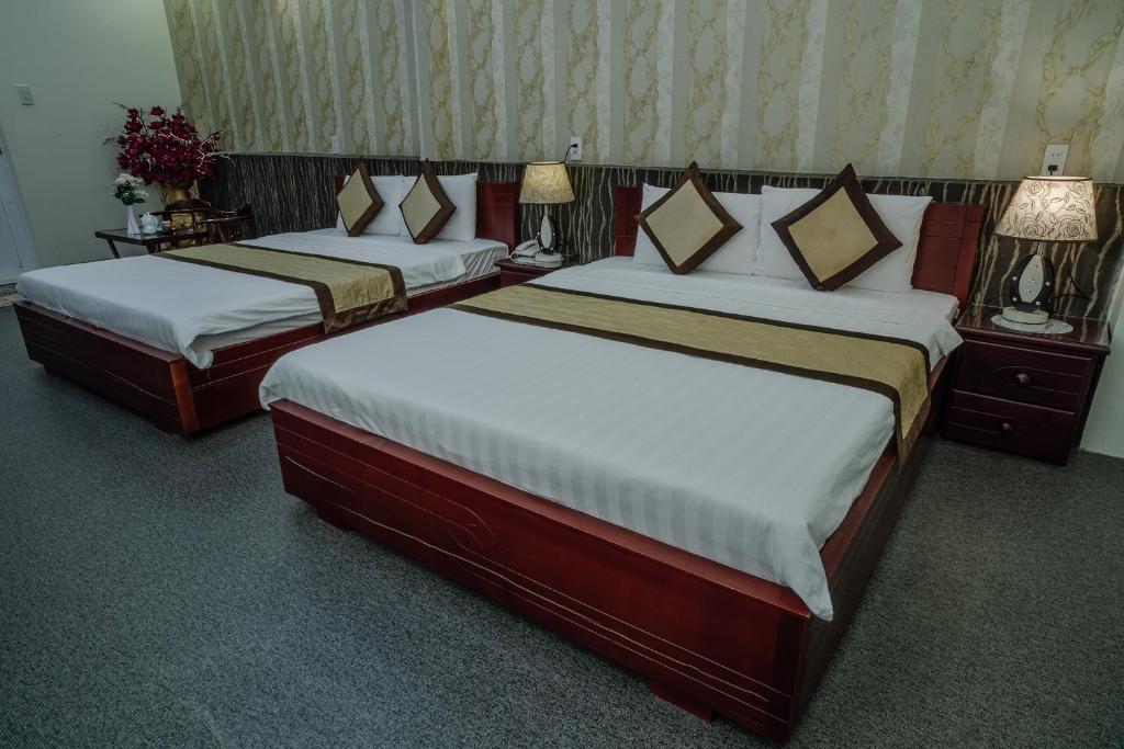 two beds in a hotel room with two lamps at Dong Bao Hotel in Chau Doc