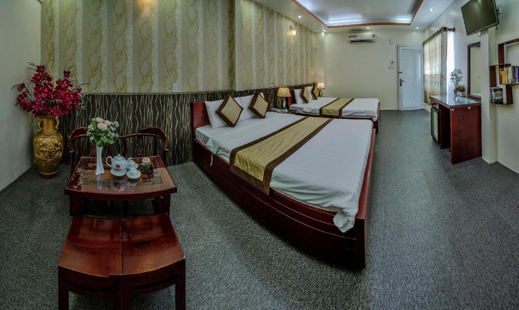 a hotel room with a large bed and a table at Dong Bao Hotel in Chau Doc