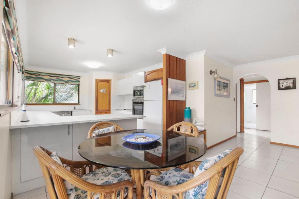 a kitchen and dining room with a glass table and chairs at Sha na na Unit 3 Kings Beach Gem in Caloundra