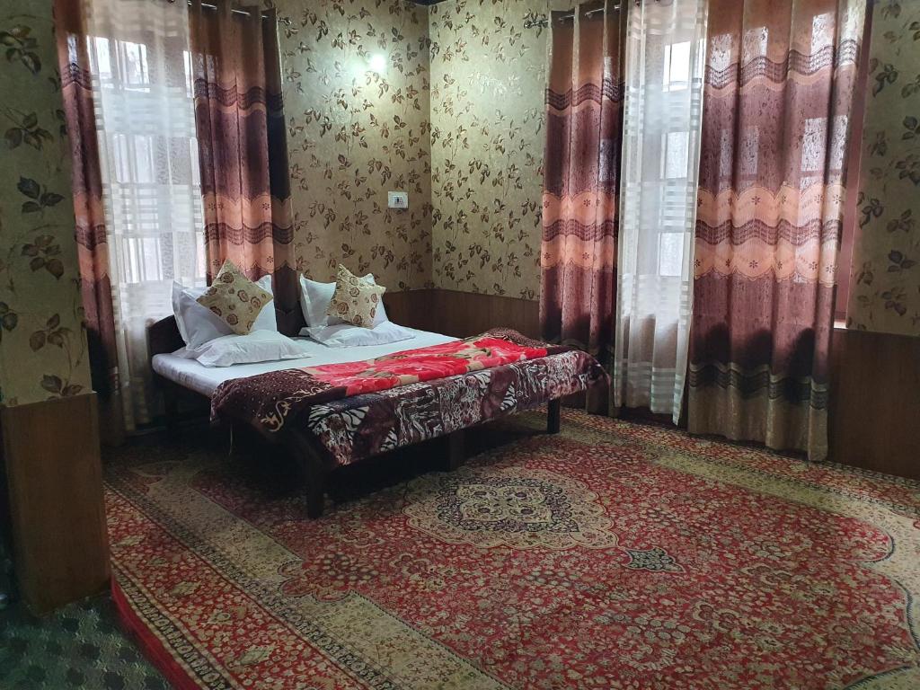 a bedroom with a bed with curtains and a red rug at Hotel Wazir Palace in Srinagar