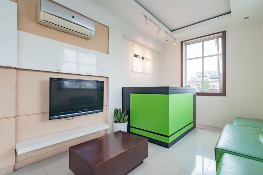 sala de estar con TV de pantalla plana grande en Urbanview Hotel Syariah Dapen Pontianak by RedDoorz, en Siantan
