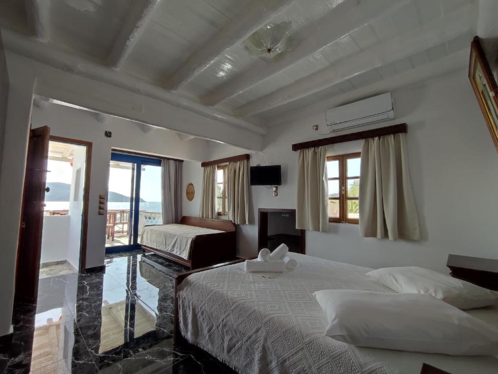a hotel room with two beds and a balcony at Alexandros by the Beach - Serifos in Livadakia