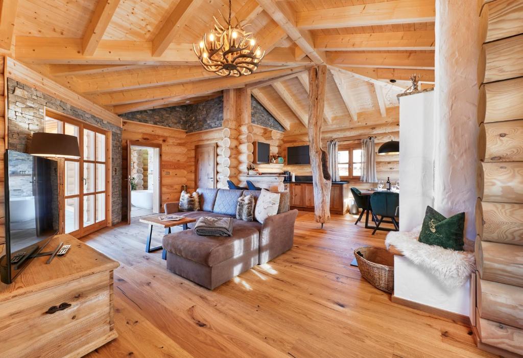 ein Wohnzimmer mit einem Holzhaus, einem Sofa und einem TV in der Unterkunft Lederer Chalets in Bodenmais