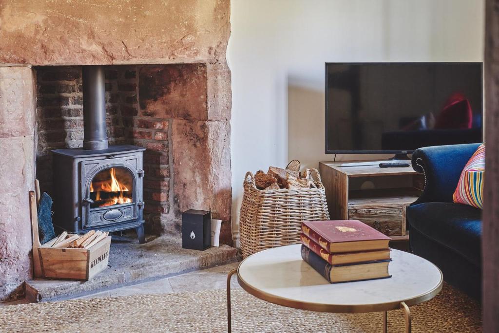 a living room with a fireplace and a tv at Lakeside Cottage in Nantwich
