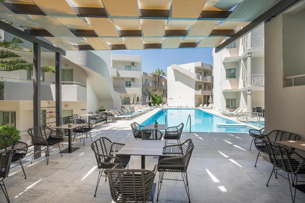 eine Außenterrasse mit Tischen und Stühlen sowie einem Pool in der Unterkunft Summer Beach Hotel in Georgioupoli