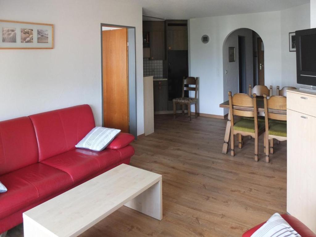 a living room with a red couch and a table at Bergblick 35 in Bolgen