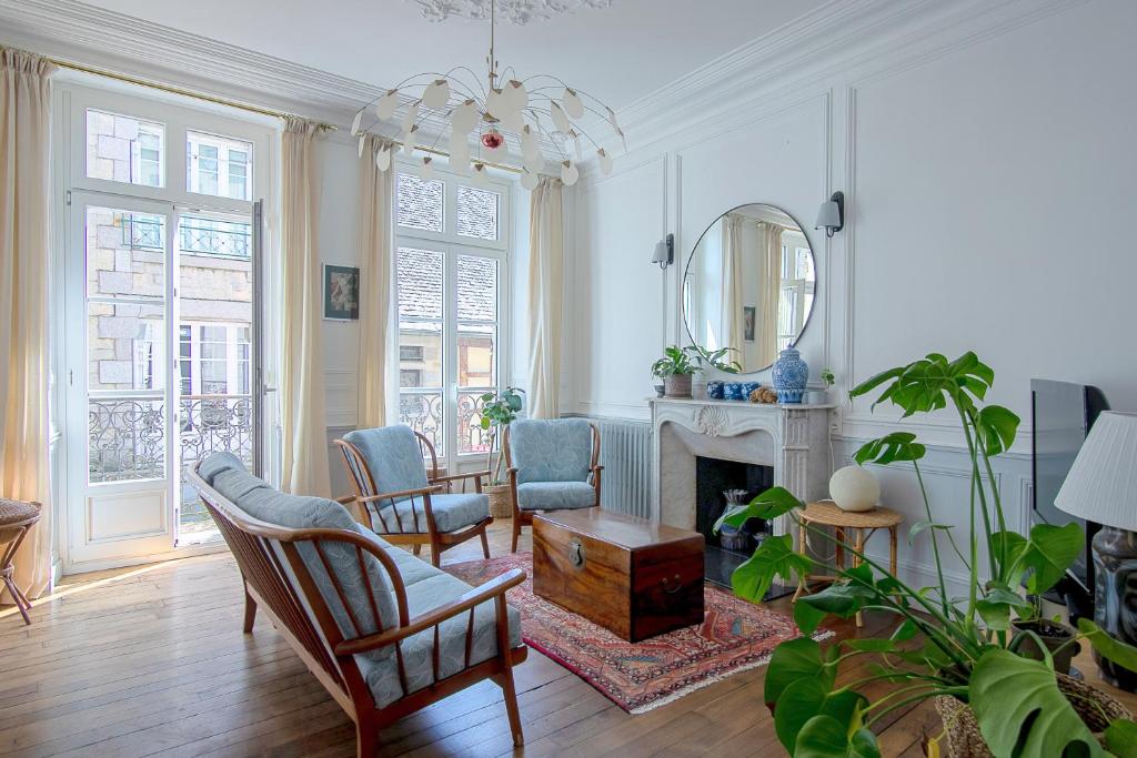 a living room with a fireplace and chairs and a mirror at Appartement de la Tour de l'Horloge de DINAN in Dinan