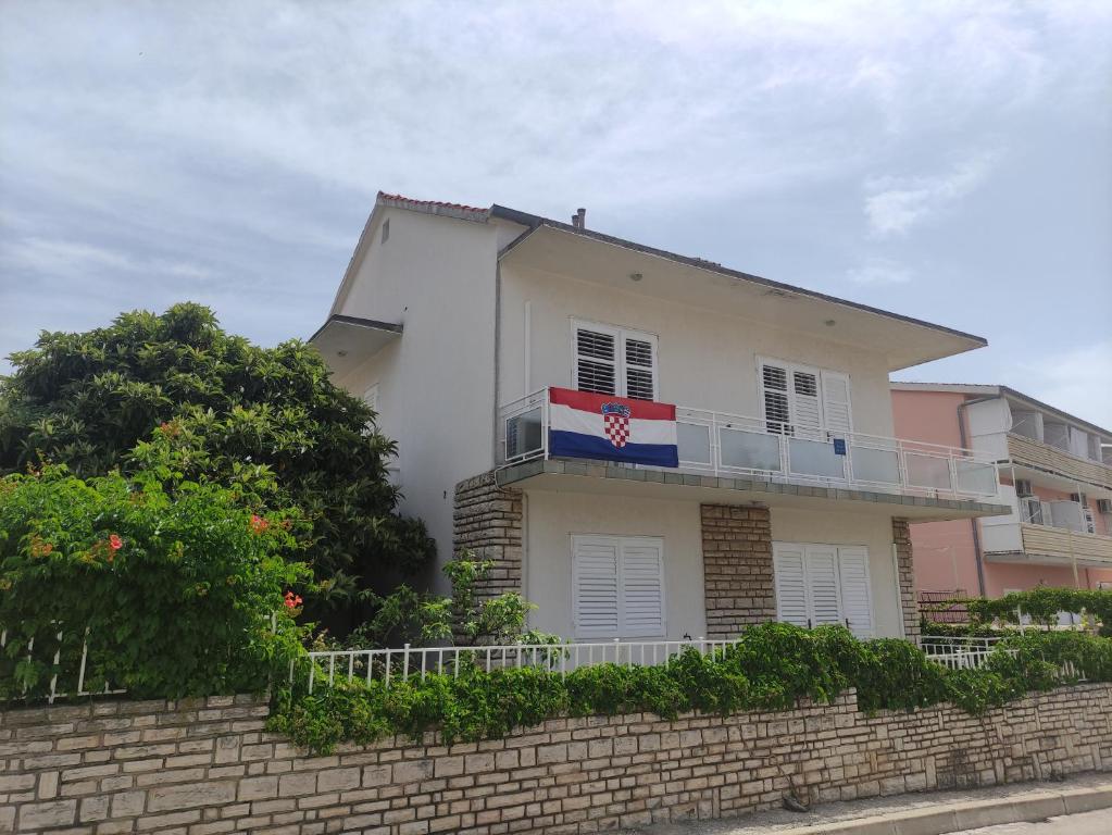 Casa blanca con bandera en el balcón en Apartment Landeka en Primošten