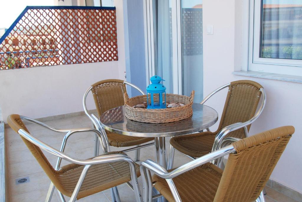 a glass table with chairs and a blue bottle on it at Thalassenia Studios in Hanioti
