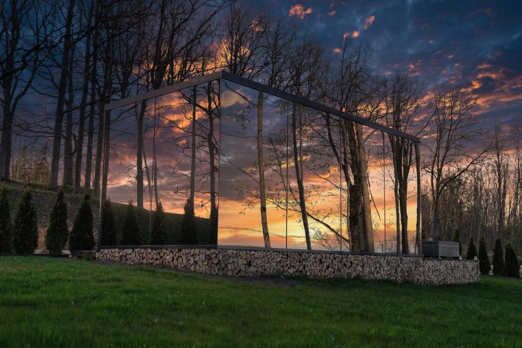 a glass house with a sunset in the background at 7Mirrors in Skrīveri