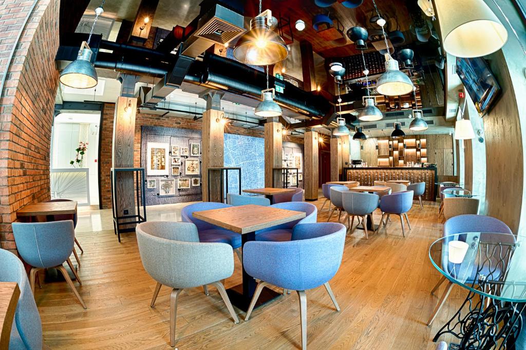 ein Restaurant mit blauen Stühlen und Tischen in einem Raum in der Unterkunft Hotel The Loom in Łódź