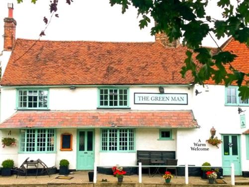 um edifício branco com uma placa que lê o seu máximo jardim em The Green Man Boutique Hotel em Takeley