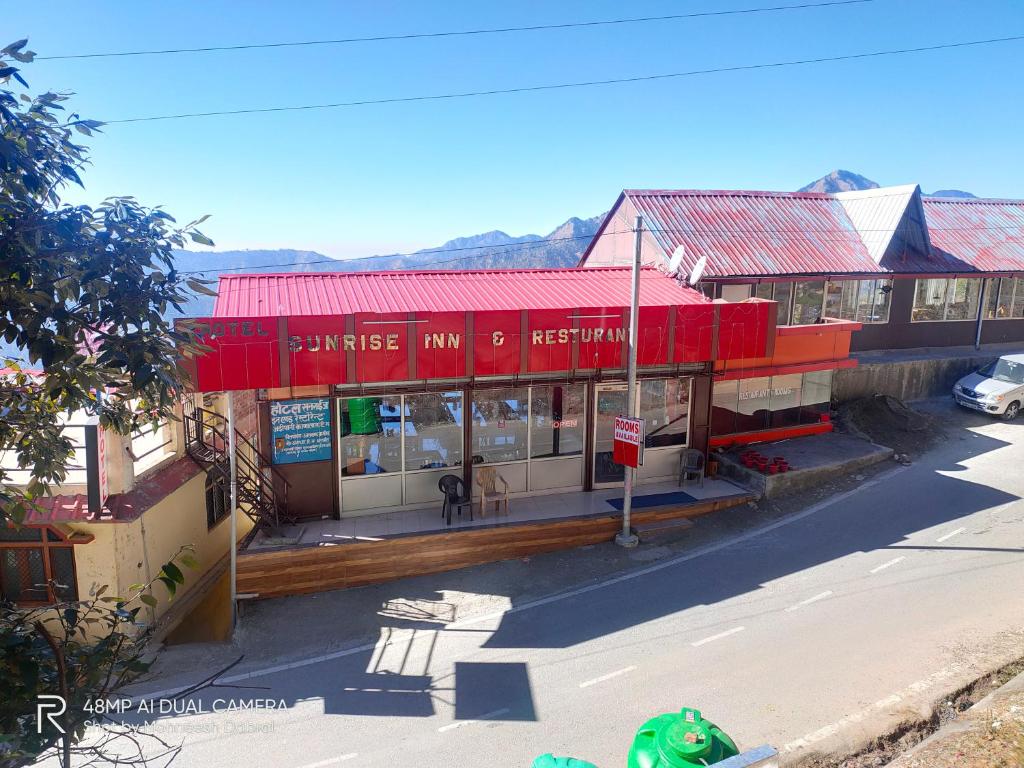 een uitzicht op een gebouw met een rood dak bij Hotel Sunrise Inn & Restaurant, Kanatal in Chamba