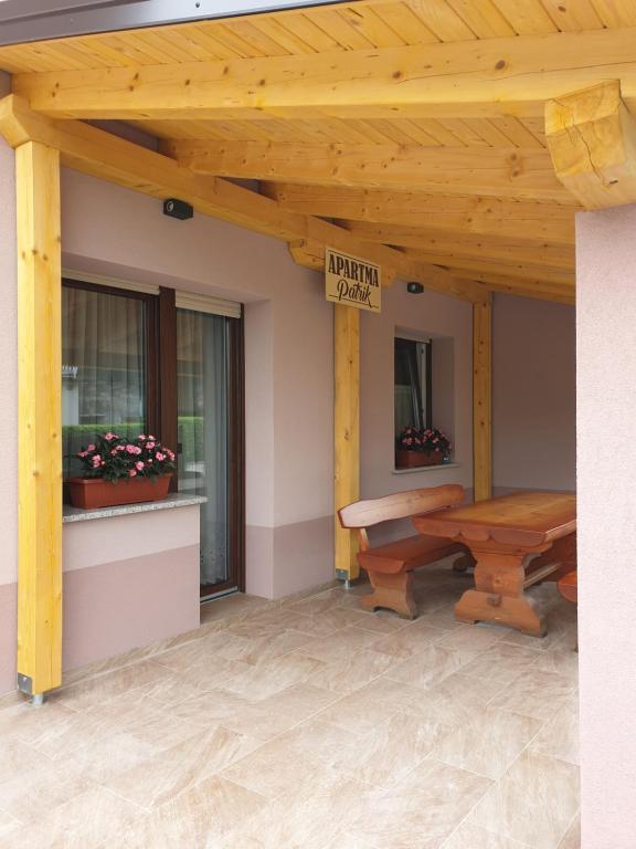 un porche de madera con una mesa de picnic y un cartel en Apartma Patrik en Kobarid