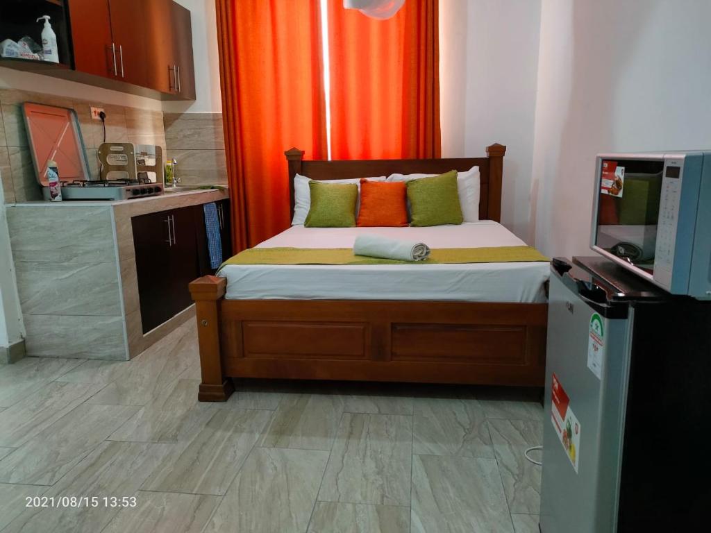 1 dormitorio con 1 cama con cortina naranja en Mtwapa Pride Studio Apartment 33, en Mtwapa