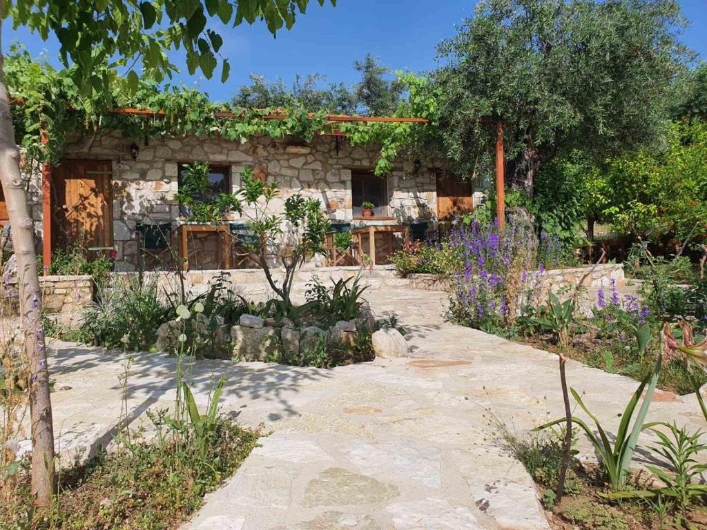 a stone house with a garden with purple flowers at Filoxenia Holiday in Himare