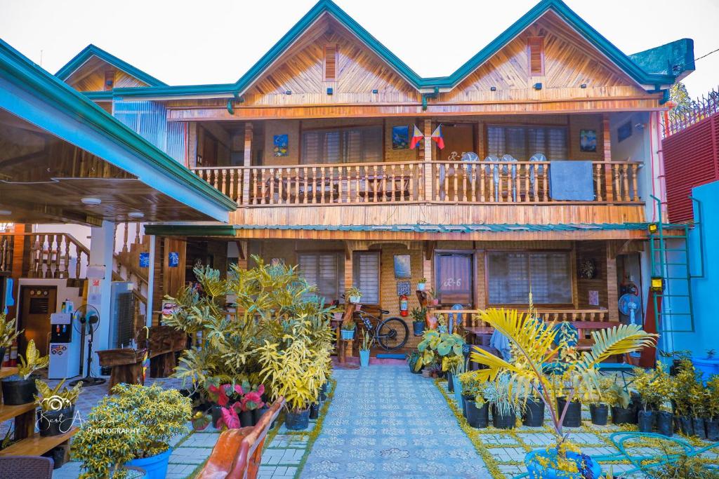 a large wooden house with a balcony and plants at Aquarius - Port Barton in San Vicente