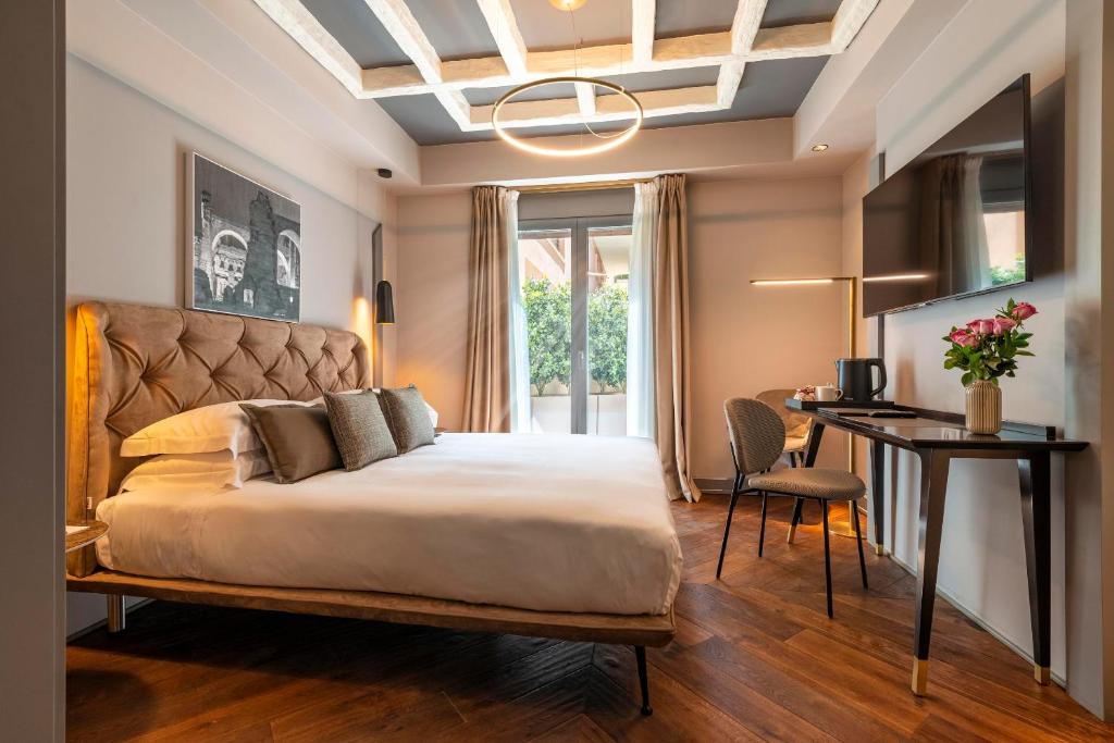 a bedroom with a large bed with a desk and a chair at Loly Boutique Hotel Roma in Rome