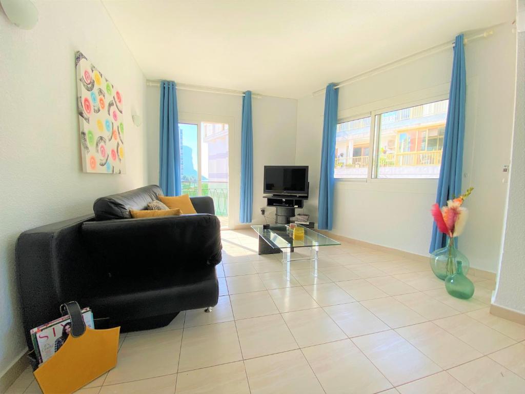 - un salon avec un canapé noir et une télévision dans l'établissement Apartamento PAOLA Calpe, à Calp