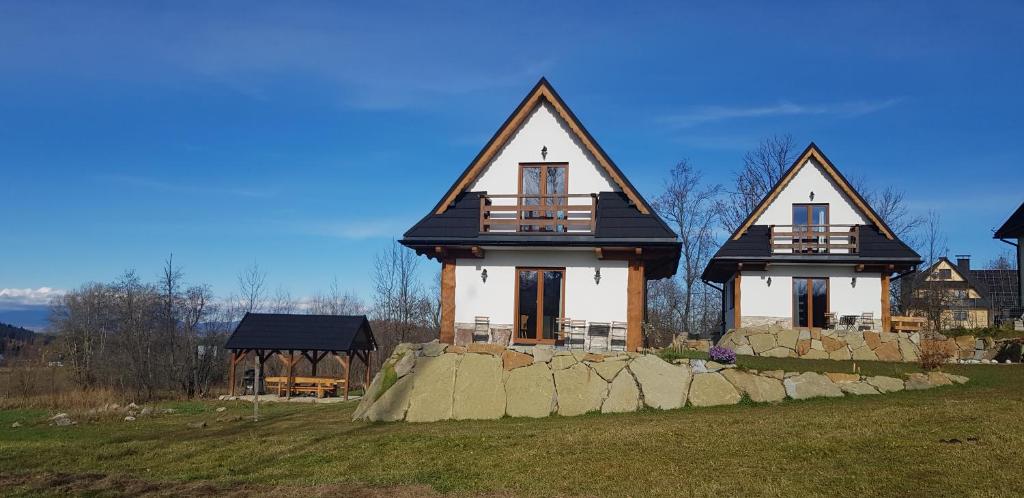 a house with a stone wall in front of it at NowiNowe Domki in Dzianisz