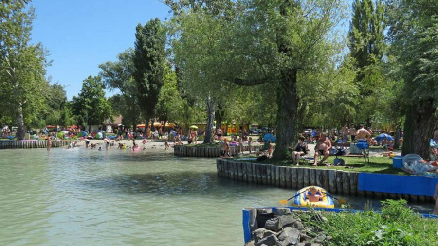 un grupo de personas sentadas alrededor de un estanque en un parque en Family Vendégház, en Balatonszárszó