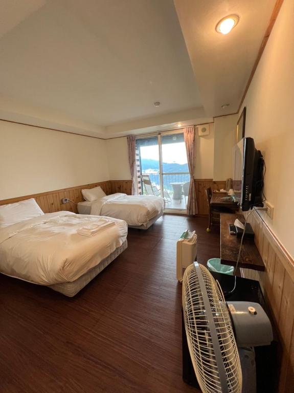 a hotel room with two beds and a television at Cingjing Four Seasons B&amp;B in Ren&#39;ai