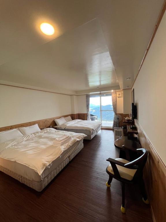 a bedroom with two beds and a desk and a chair at Cingjing Four Seasons B&amp;B in Ren&#39;ai