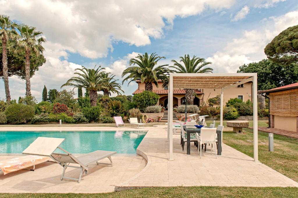 eine Terrasse mit einem Tisch und Stühlen neben einem Pool in der Unterkunft Villa delle Palme in Cecina