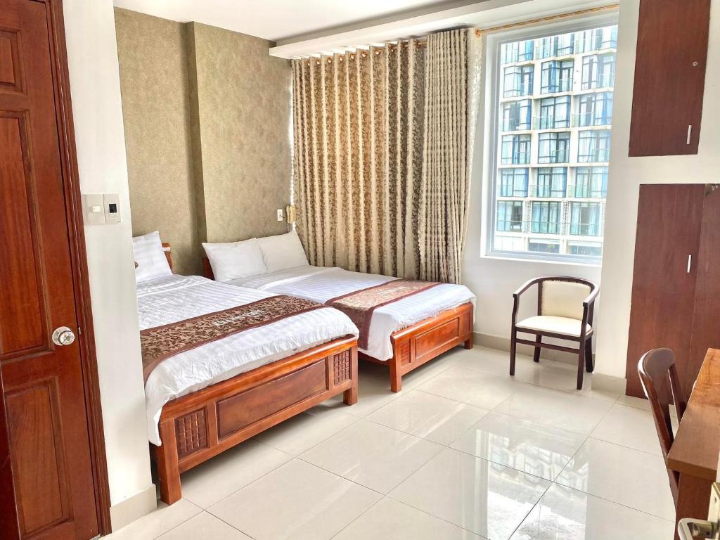 een slaapkamer met een bed, een stoel en een raam bij Khánh Vinh Hotel in Da Nang