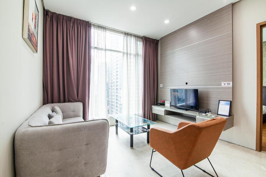 a living room with a couch chair and a television at Soho Suites @ KLCC in Kuala Lumpur