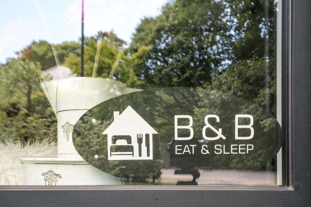 Una finestra con un cartello che dice "BBC mangia e dormi" di B&B Eat&Sleep a Evergem