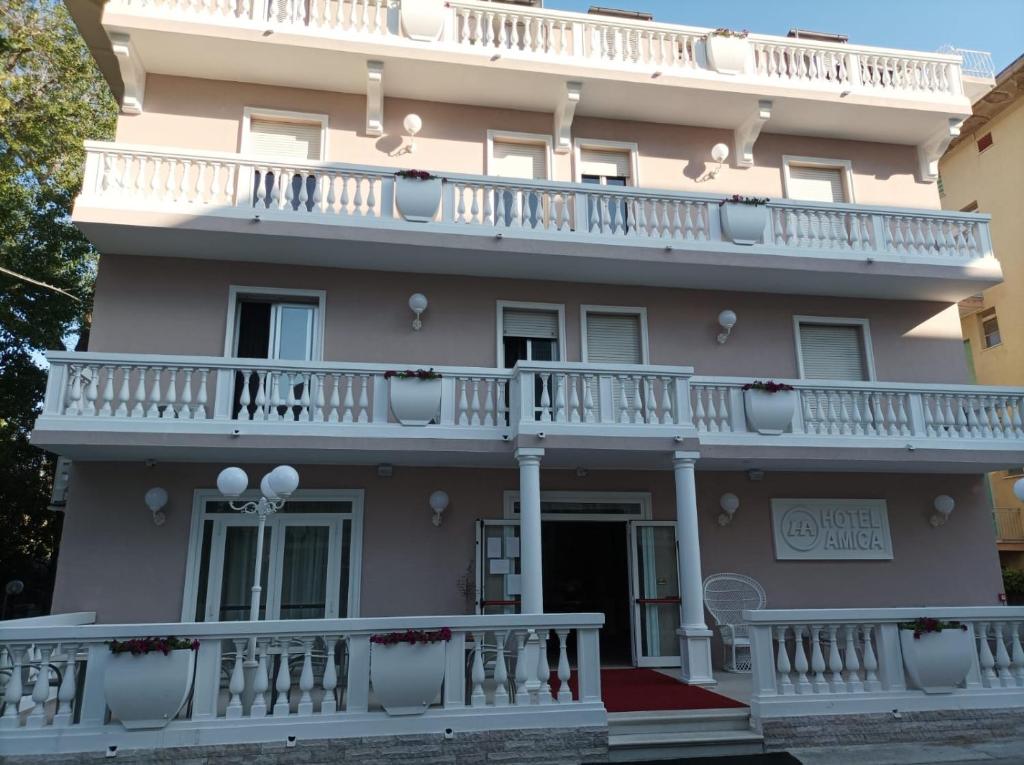 a large pink building with a white balcony at Hotel Amica in Rimini