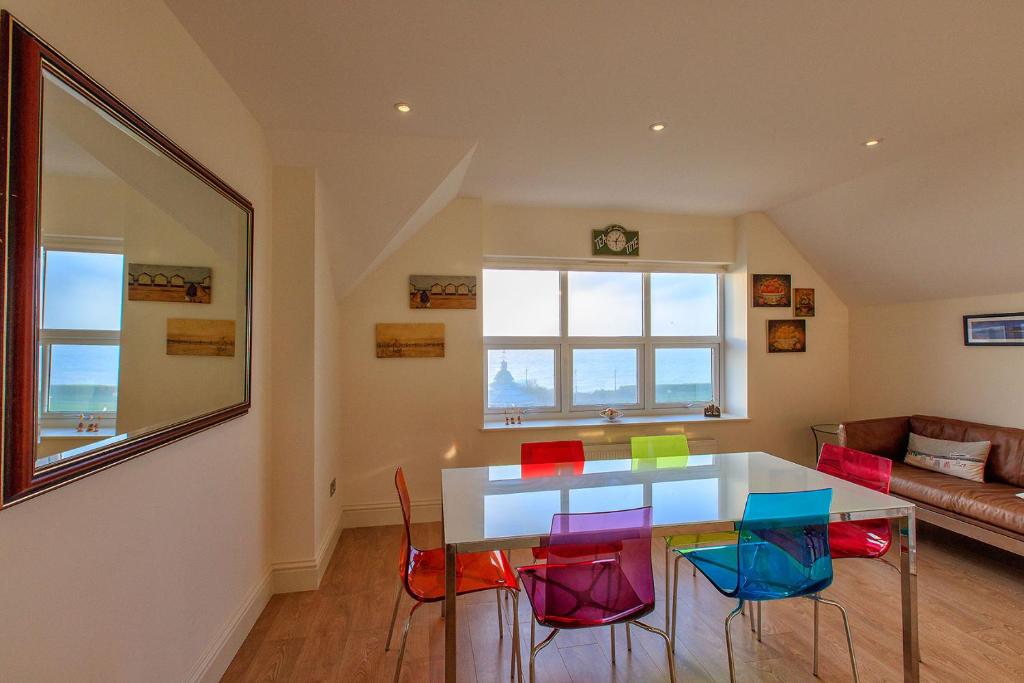 a dining room with a table and colorful chairs at Victoria Parade: Perfect family apartment over looking Viking Bay, stones throw from the beach and town in Broadstairs
