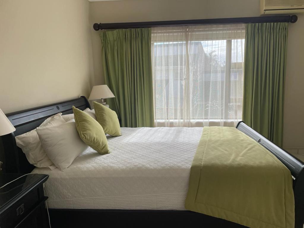 a bedroom with a bed with green curtains and a window at Trevi Sea-view Apartment in Margate