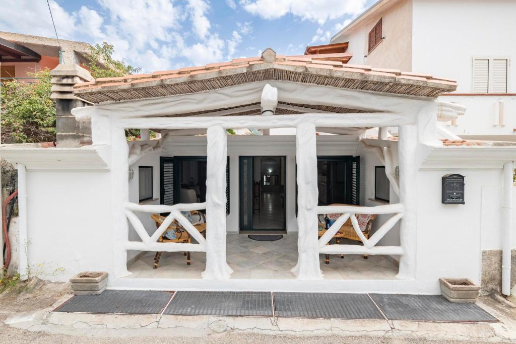 a white house with a porch and columns at Appartamento Holiday in Cala Gonone