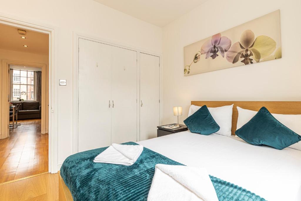 una camera da letto con un grande letto con cuscini blu di Mansion House Apartments a Londra