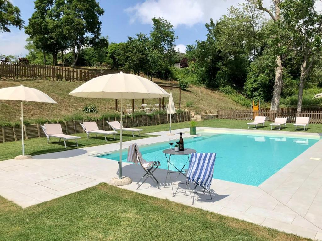 - une piscine avec une table, des chaises et des parasols dans l'établissement Podere Fabbrani, à Pennabilli