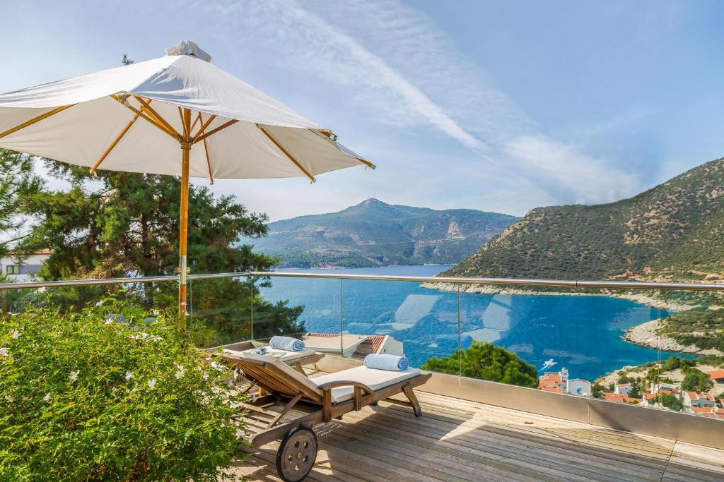 un patio con sombrilla y sillas y vistas al agua en Happy Hotel Kalkan, en Kalkan