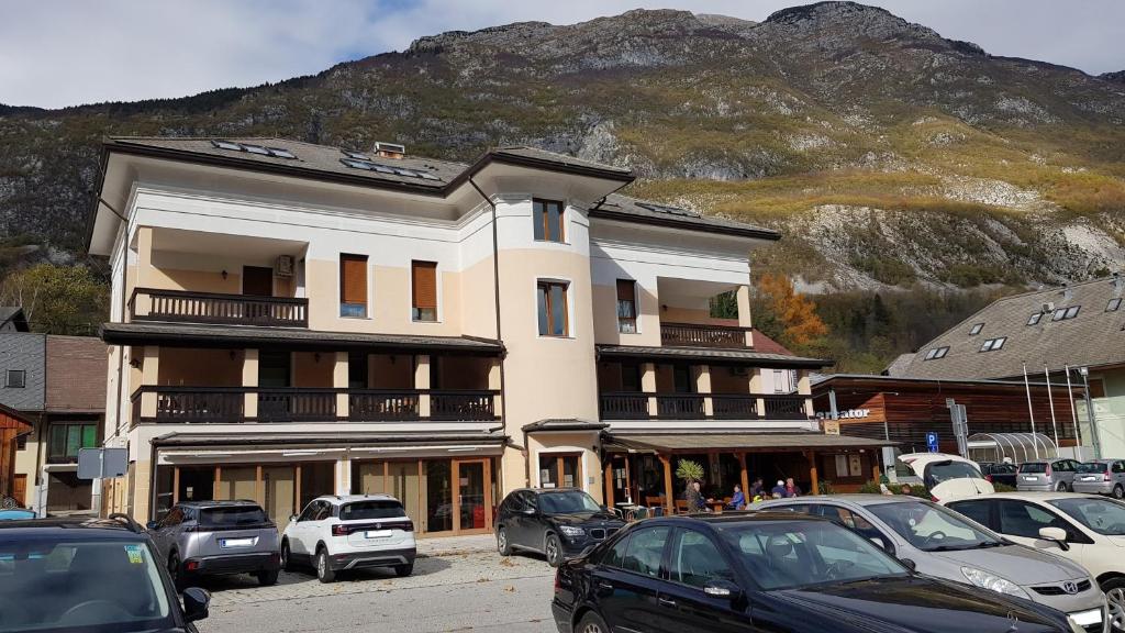 een groot gebouw met auto's geparkeerd op een parkeerplaats bij Apartma Valan in Bovec