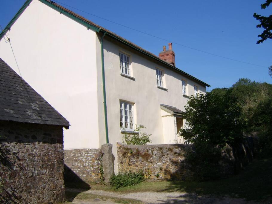 uma grande casa branca com uma parede de pedra em Farmer Bob's Farmhouse em Barnstaple